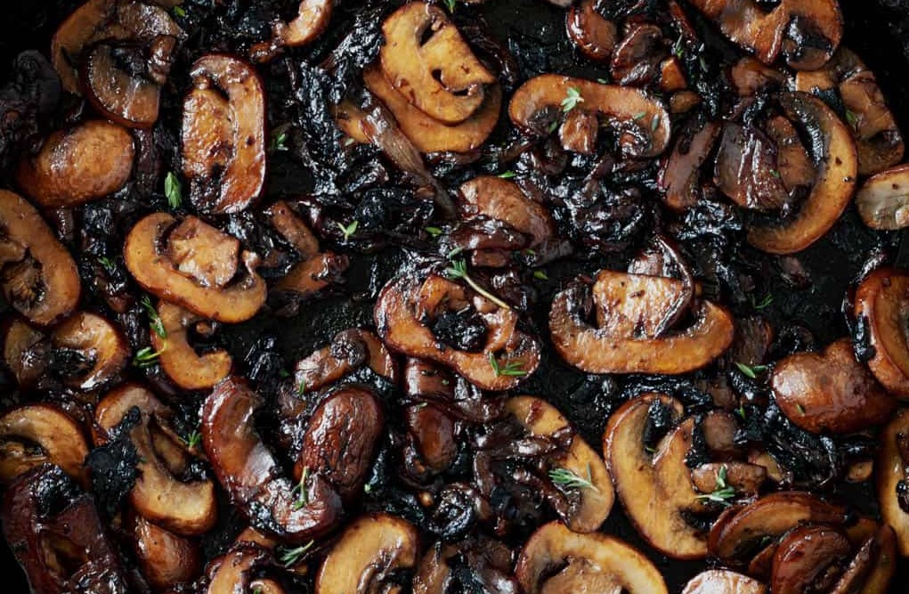 Close-up of sautéed mushrooms with caramelized onions on a Blackstone griddle, served as a savory side dish for steak. Easy RV-friendly recipe.”